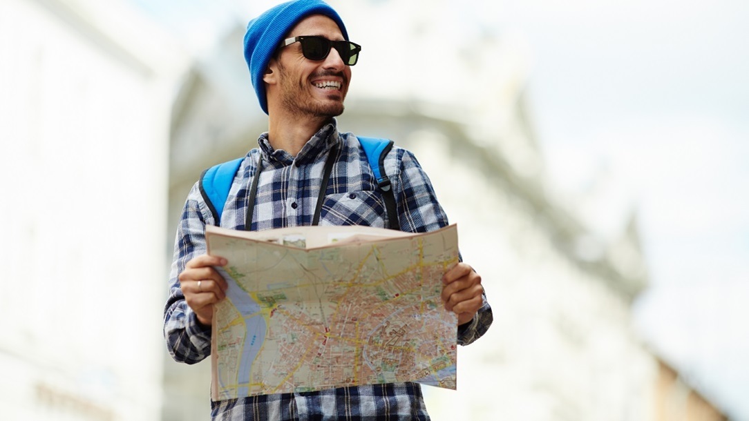 Happy man wearing sunglasses using a map