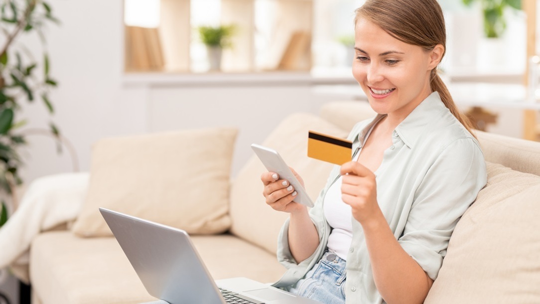 Woman smiling as she checks credit card and laptop