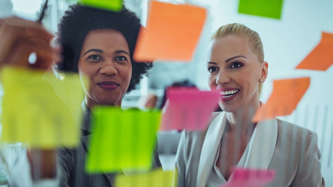 Two businesswomen looking at coloured Post-it notes